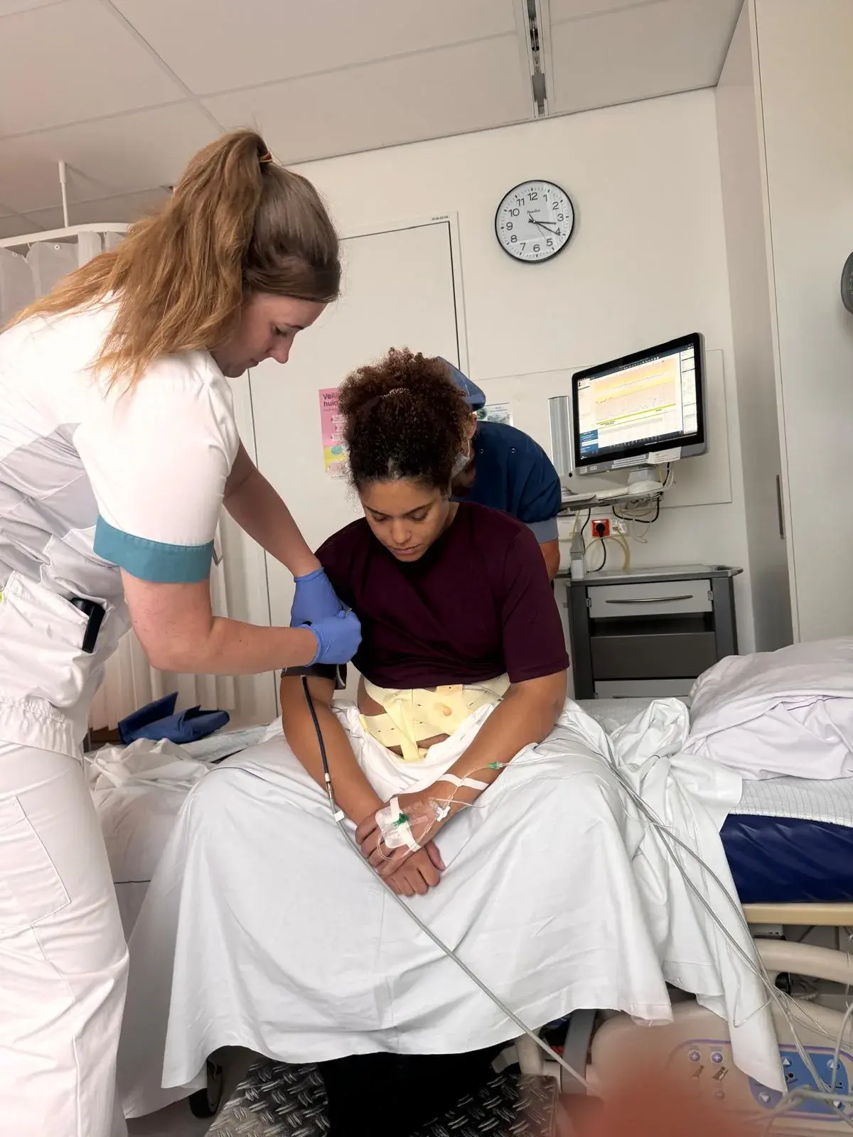 Kyle sitting on the edge of her hospital bed while receiving her epidural