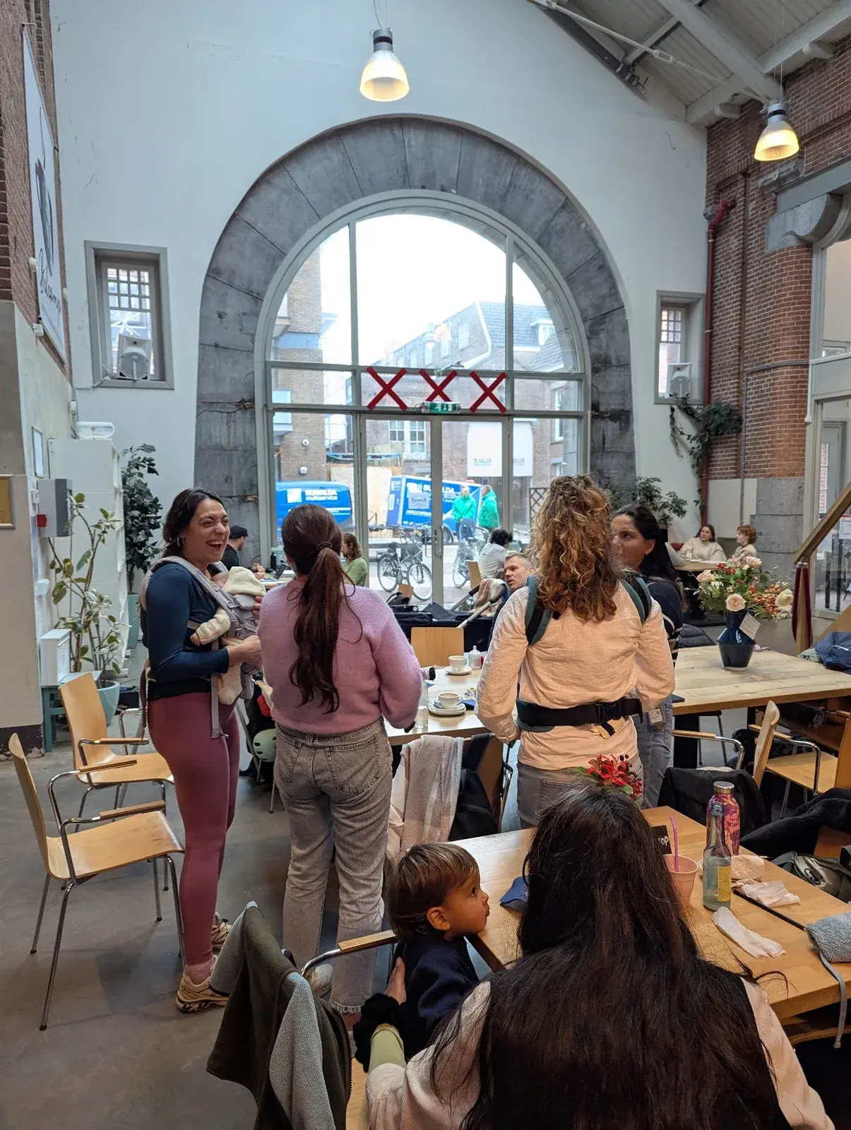 Parents chatting and holding babies at a De Hallen café meetup