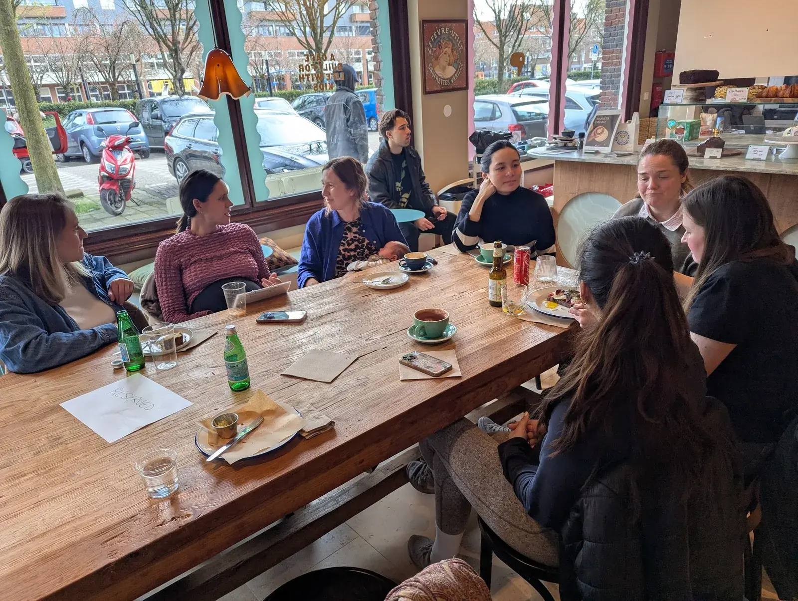 A group of parents gathered around a café table for a social meetup